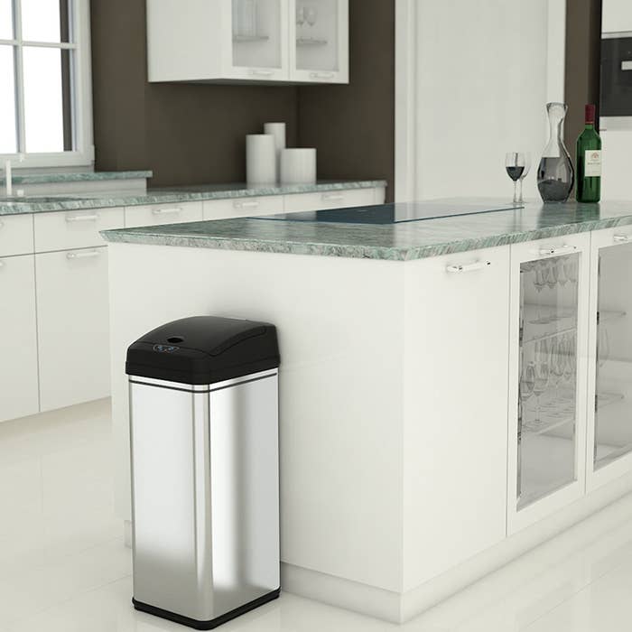 Modern kitchen with white cabinets and a sleek, touchless trash can model