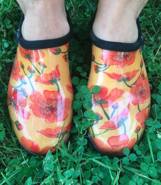 Reviewer's yellow clogs with red flowers are displayed in grass
