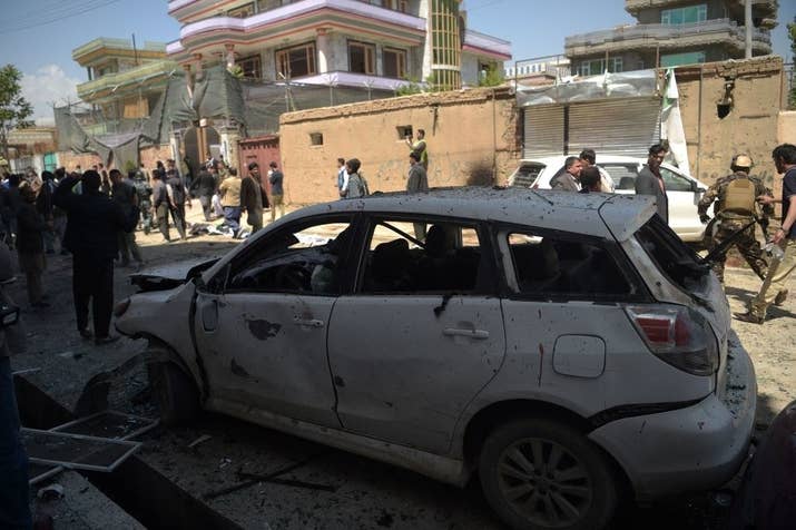 Afghan residents inspect the site of a suicide bombing outside a voter registration center in Kabul on April 22, 2018.