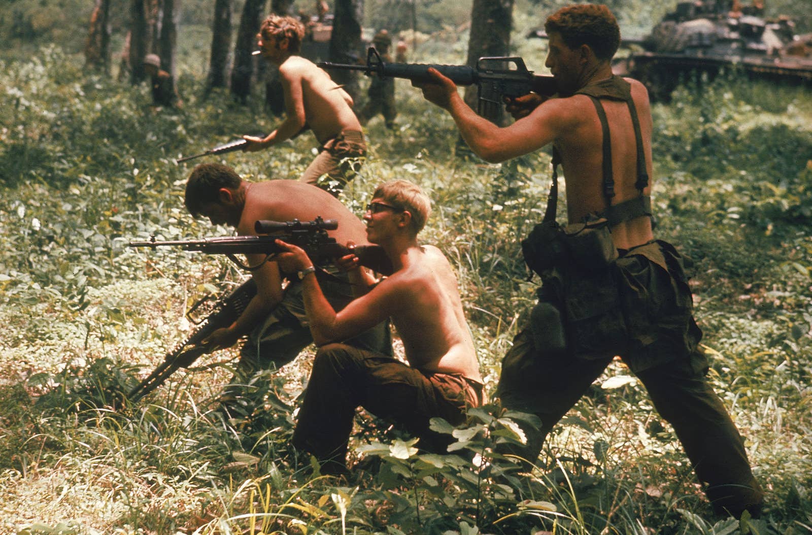 Sem camisas, soldados americanos da 9ª Divisão de Infantaria atiram contra tropas inimigas em algum local na fronteira entre Vietnã e Camboja.