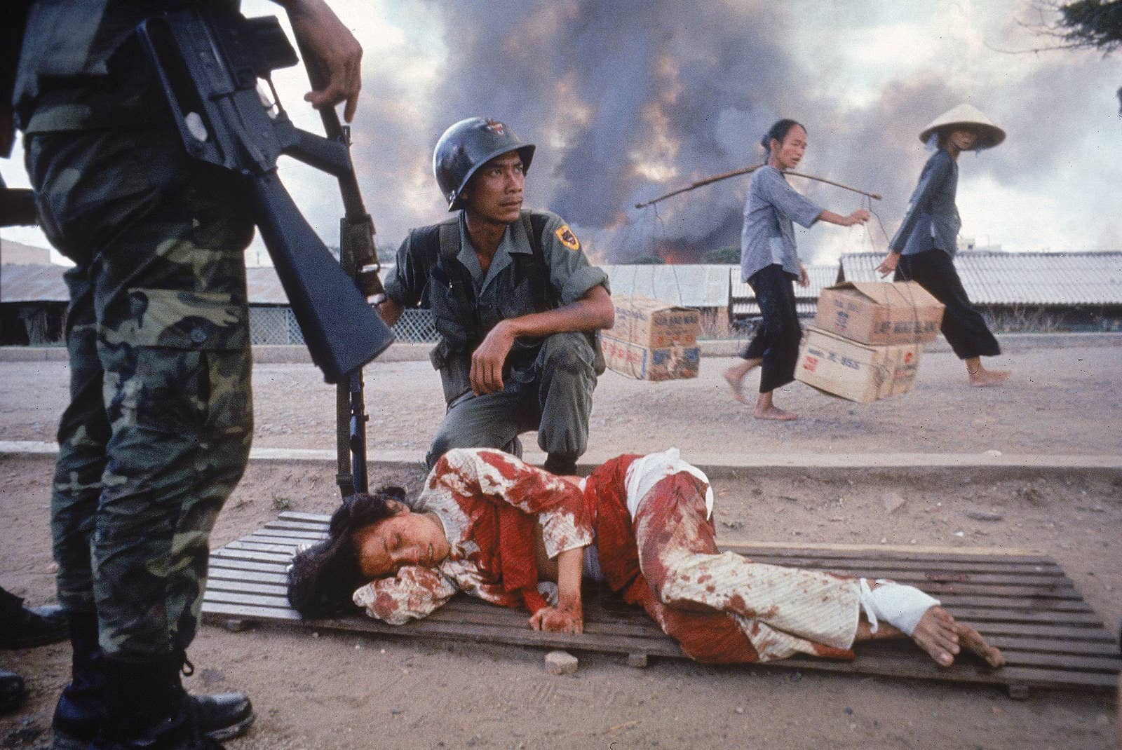 Soldado sul-vietnamita observa mulher ferida enquanto aguarda assistência médica, durante um ataque de vietcongues.