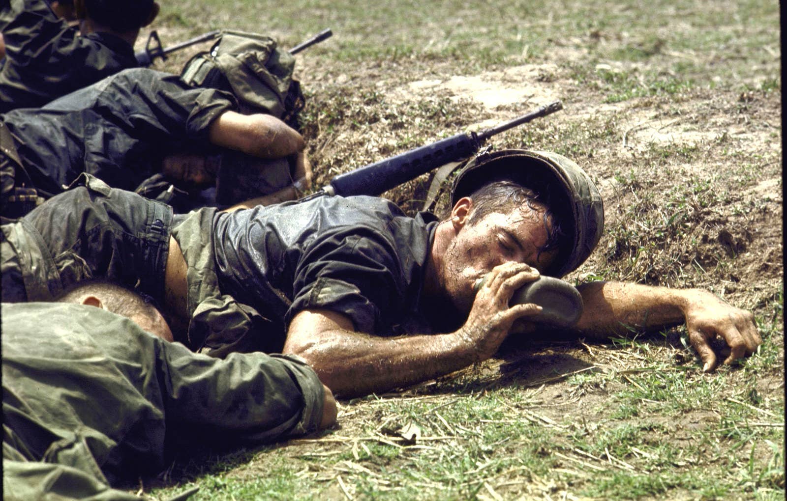 Exausto, um soldado da infantaria americana deita entre camaradas e bebe água de um cantil, próximo à fronteira entre Vietnã e Camboja, em 1970.