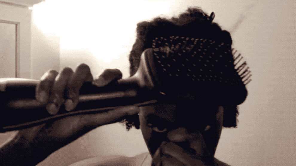 A GIF of a person drying and straightening their hair with a hot styling brush