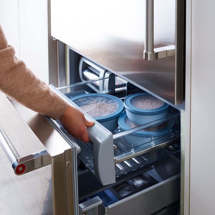 hand pulling the containers out of a freezer drawer