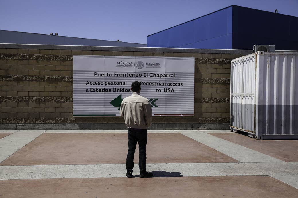 Noel, a teenager from Honduras, looks at the sign pointing to the United States from Tijuana.