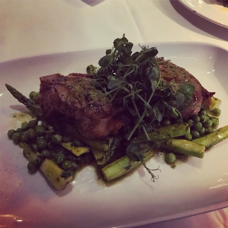 Two pieces of bone-in lamb loin chop - cooked perfectly to the temperature of your choice - is served with asparagus and peas with sauce colbert