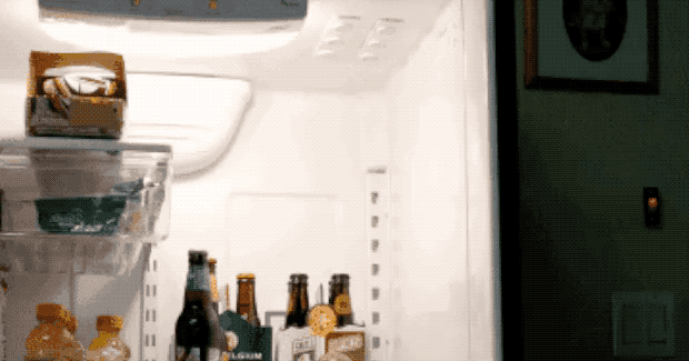 a gif of someone placing a six pack of bottles into the top of the fridge using the magnets