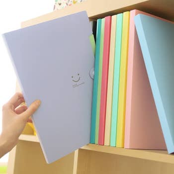 purple accordion folder with smiley face being pulled from bookshelf 