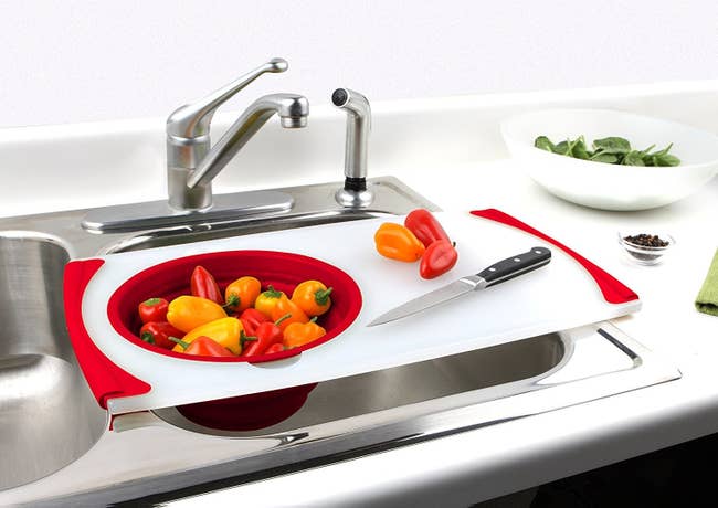 The cutting board and strainer with peppers over the sink