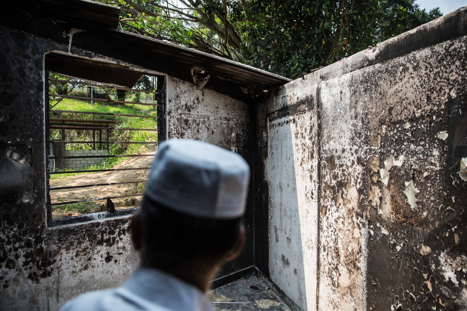A man looks out of a burned out window at Masjidul Lafir Jummah Mosque in Digana. The attacks there were carried out by Buddhist mobs only a few weeks earlier on March 7, leaving many homes and shops destroyed and one young man dead.