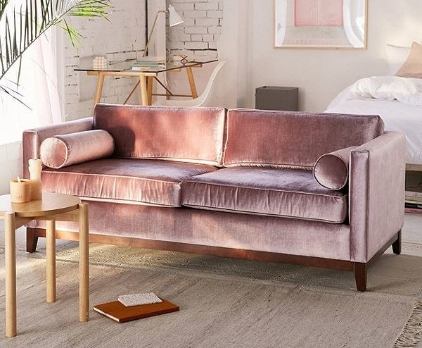 The pink velvet sofa on display with a coffee table