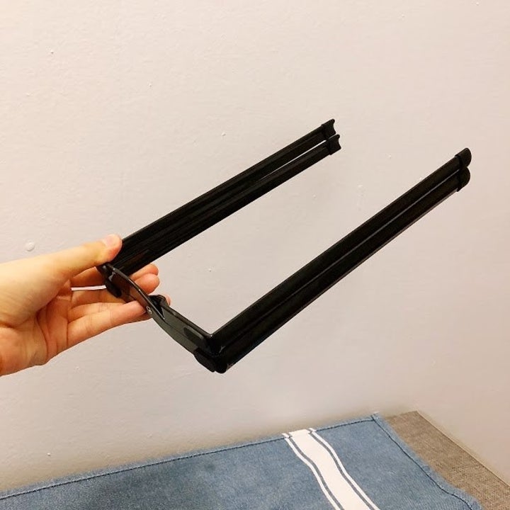 A person holding the collapsed multiuse rack