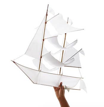 A completed origami ship kite held in a model's hand