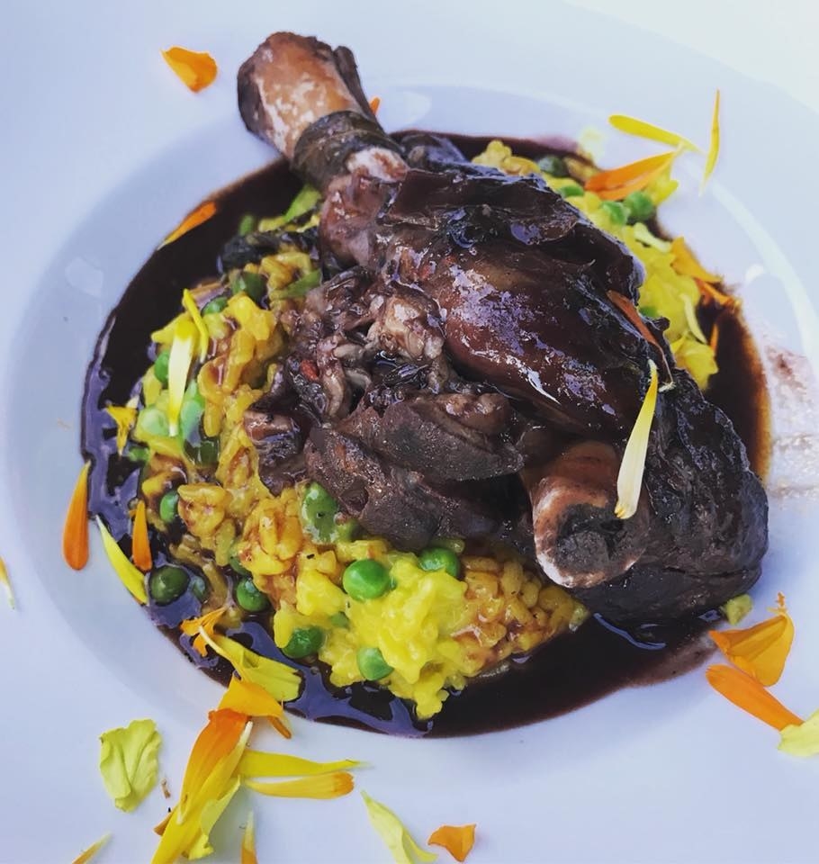 The fall-off-the-bone, tender lamb shank is served atop rich, hearty saffron risotto with green peas and asparagus in rich port wine sauce.