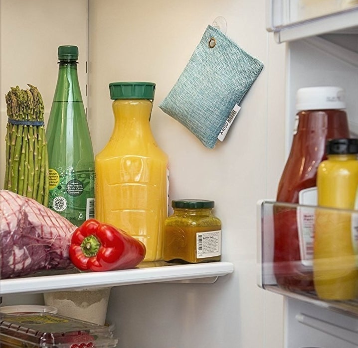 A small rectangular fabric pouch hanging by a hook on the inside of a fridge 