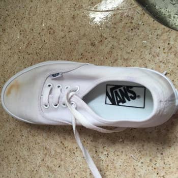 reviewer's white Vans with dirt stain