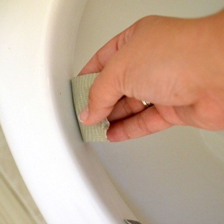 hand placing duct tape under rim of toilet