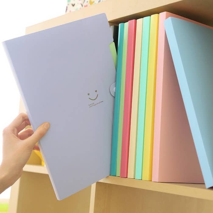 a person putting a lavender folder on the shelf with other accordion folders 