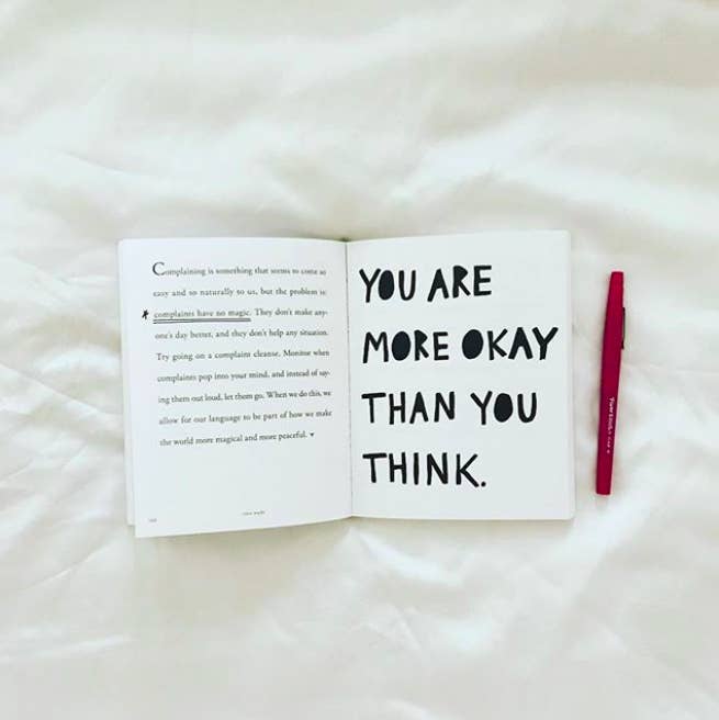 A book opened to a page that says, &quot;You are more okay than you think.&quot;