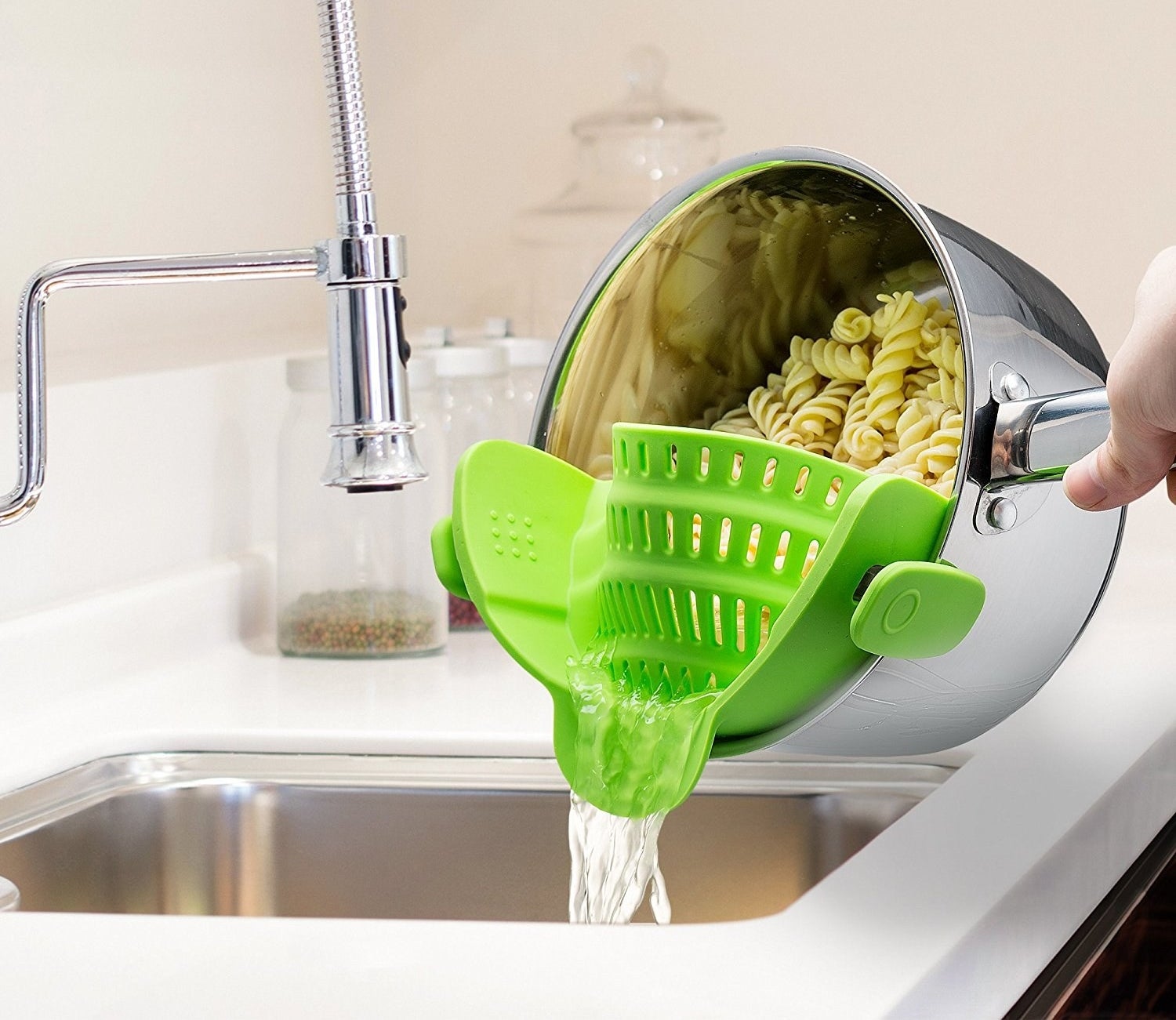 a pot of pasta being strained over a sink with the snap-on colander