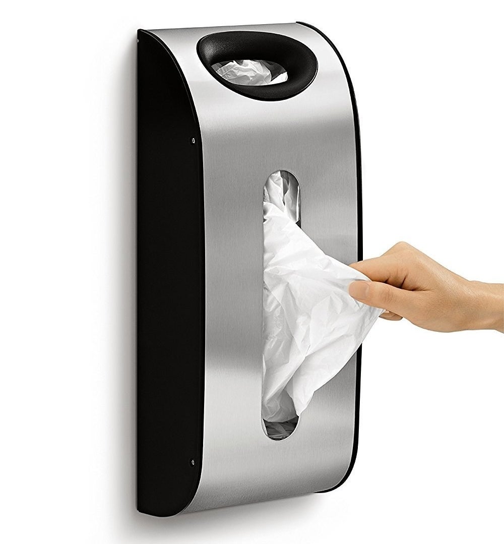 a hand removing a bag from the bag dispenser