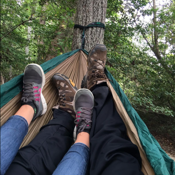 A reviewer photo of two people 's legs and feet in the hammock, which is attached to a tree