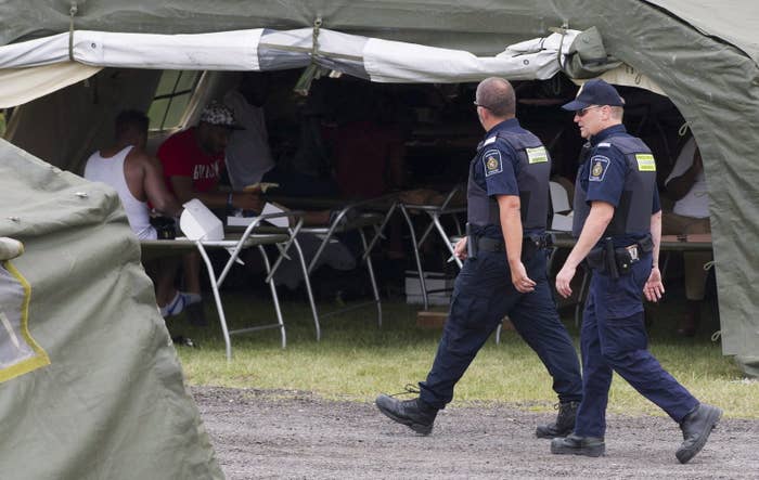 Members of the CBSA walk by a tent housing asylum seekers at the Canada–United States border in Lacolle, Quebec.