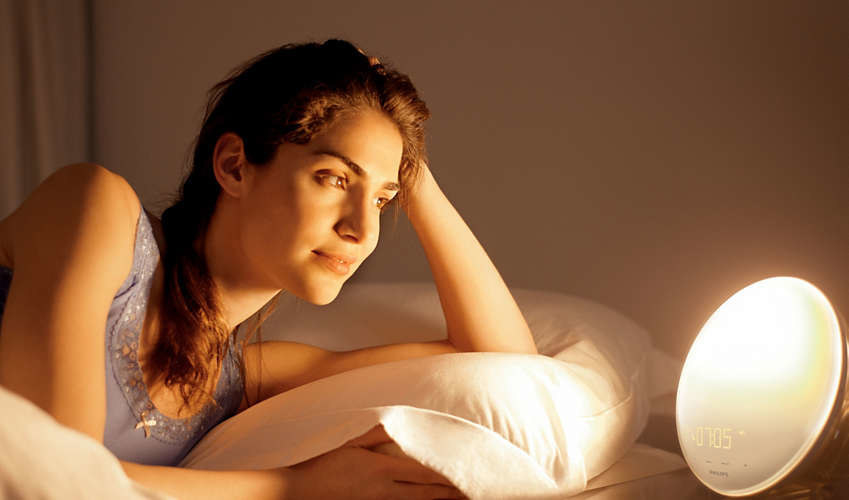 A model looking at the round alarm clock glowing brightly