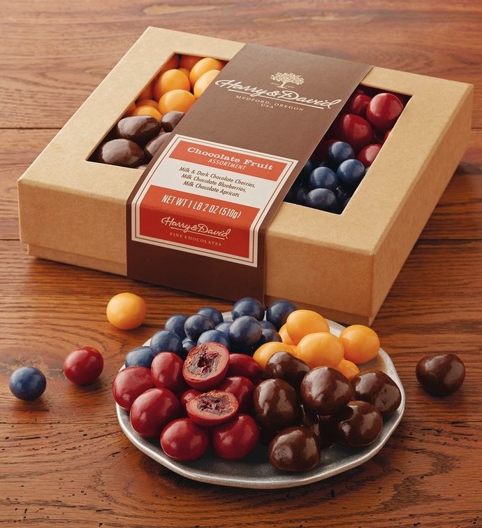 a bowl with four chocolate covered fruits in different colors 