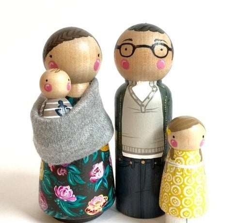 product shot of two peg parents, one holding a baby, and a peg child