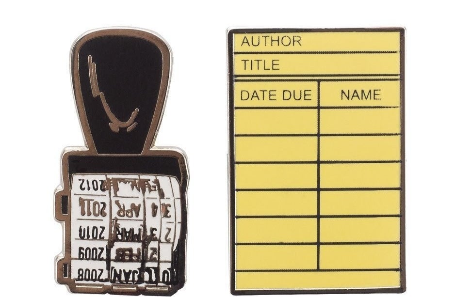 enamel pins made to look like a library stamp and library checkout card