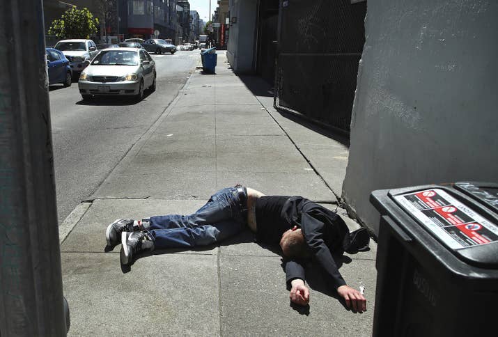 A man lies on a San Francisco sidewalk.
