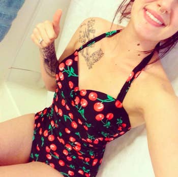 reviewer wearing the halter suit in black and red cherry print