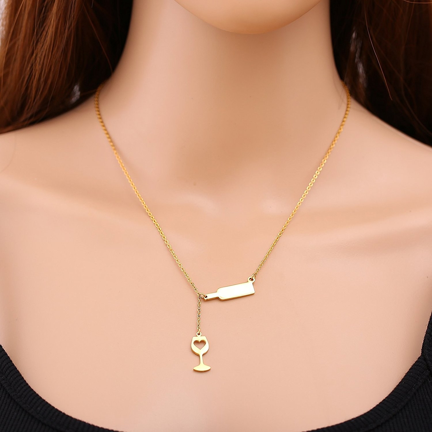 Model wearing a gold necklace with a wine charm pouring into a drop down wine glass charm 