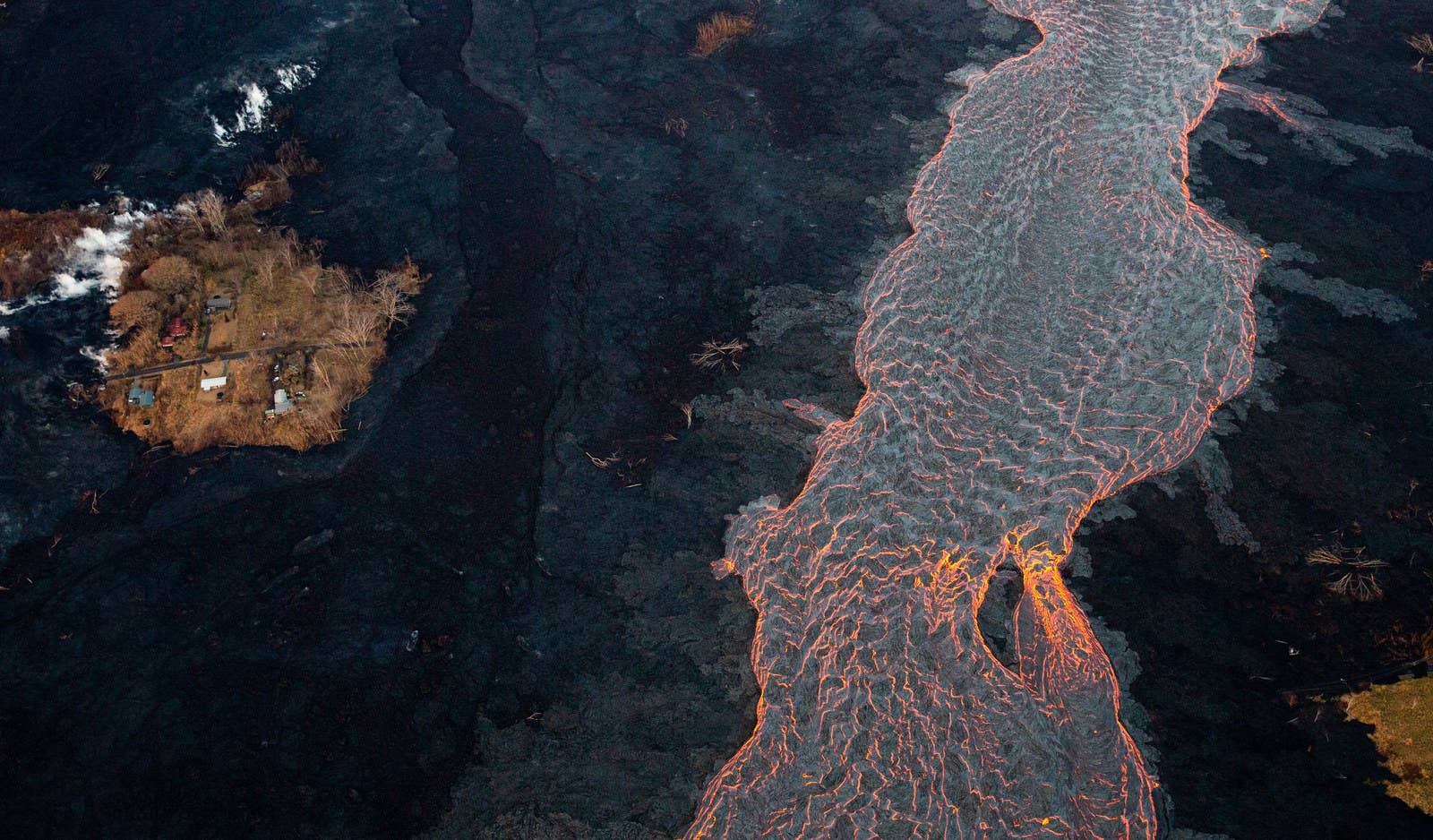 A channel of lava flows near a &quot;kipuka,&quot; or island of untouched homes.