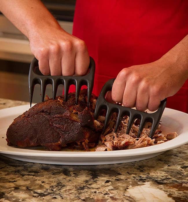 Hands using the black claws to shred a hunk of meat