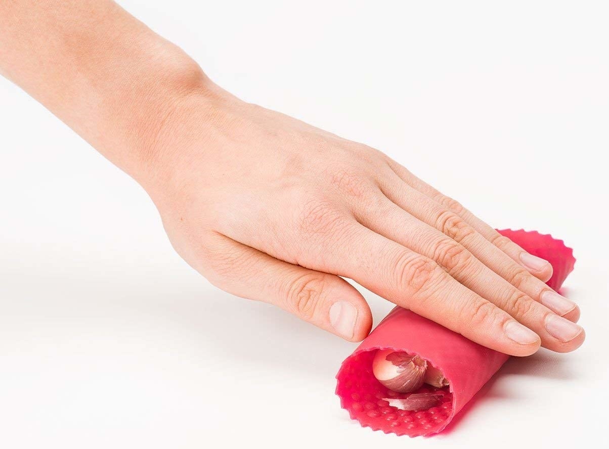 Hand rolling garlic in the red silicone tube