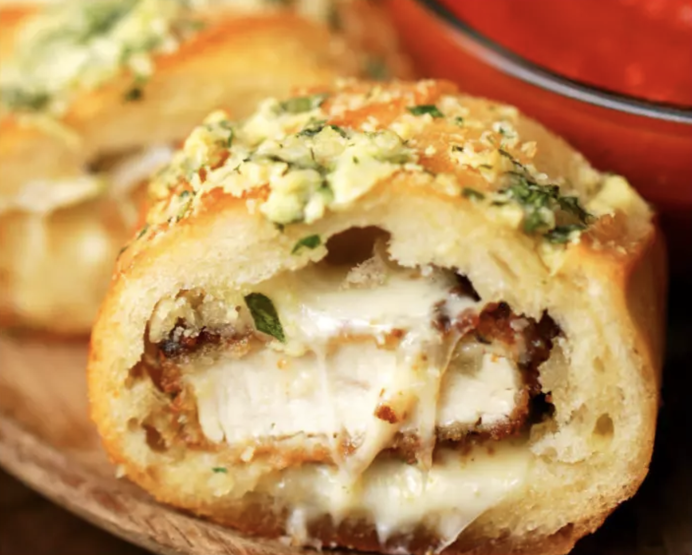 Você vai precisar de:1 peito de frango, sem osso e sem pele2 xícaras de farinha de trigo4 ovos batidos2 xícaras de farinha de rosca temperada1 xícara de óleo para fritar1 baguete grande10-12 fatias de muçarelaMolho de tomatePara a manteiga de alho:⅓ de xícara de manteiga derretida3 dentes de alho amassados1 colher de sopa de salsa, picada1 colher de sopa de parmesão raladoModo de preparo:1. Fatie o peito de frango em tiras de 1 centímetro de espessura.2. Coloque a farinha de trigo, os ovos e a farinha de rosca em 3 tigelas separadas.3. Role uma tira de frango na farinha, e tire o excesso. Molhe a tira no ovo e então coloque-a na farinha de rosca, cobrindo-a completamente.4. Repita com o frango restante.5. Aqueça óleo a 350˚F/ 180˚C e preaqueça o forno a 350°F / 180˚C.6. Frite as tiras de frango empanadas até os dois lados ficarem dourados. Coloque em papel toalha para remover o excesso de óleo.7. Fatie a baguete em pedaços aproximadamente do mesmo comprimento das tiras de frango à milanesa.8. Tire o miolo dos pedaços da baguete com uma faca.9. Coloque duas fatias de muçarela uma sobre a outra, coloque uma tira de frango empanado e dobre a muçarela bem firme em volta do frango.10. Coloque as fatias de frango enroladas dentro de um pedaço da baguete.11. Fatie os pedaços recheados da baguete e as coloque bem juntas em uma assadeira untada com óleo.12. Em uma tigela pequena, misture os ingredientes para manteiga de alho.Espalhe a manteiga de alho igualmente pelas fatias da baguete, assegurando-se de que um pouco fique entre as fatias.13. Embrulhe a baguete no papel alumínio e leve ao forno por 20-25 minutos, até o queijo derreter e o topo começar a dourar.14. Remova o papel alumínio e sirva com molho de tomate!