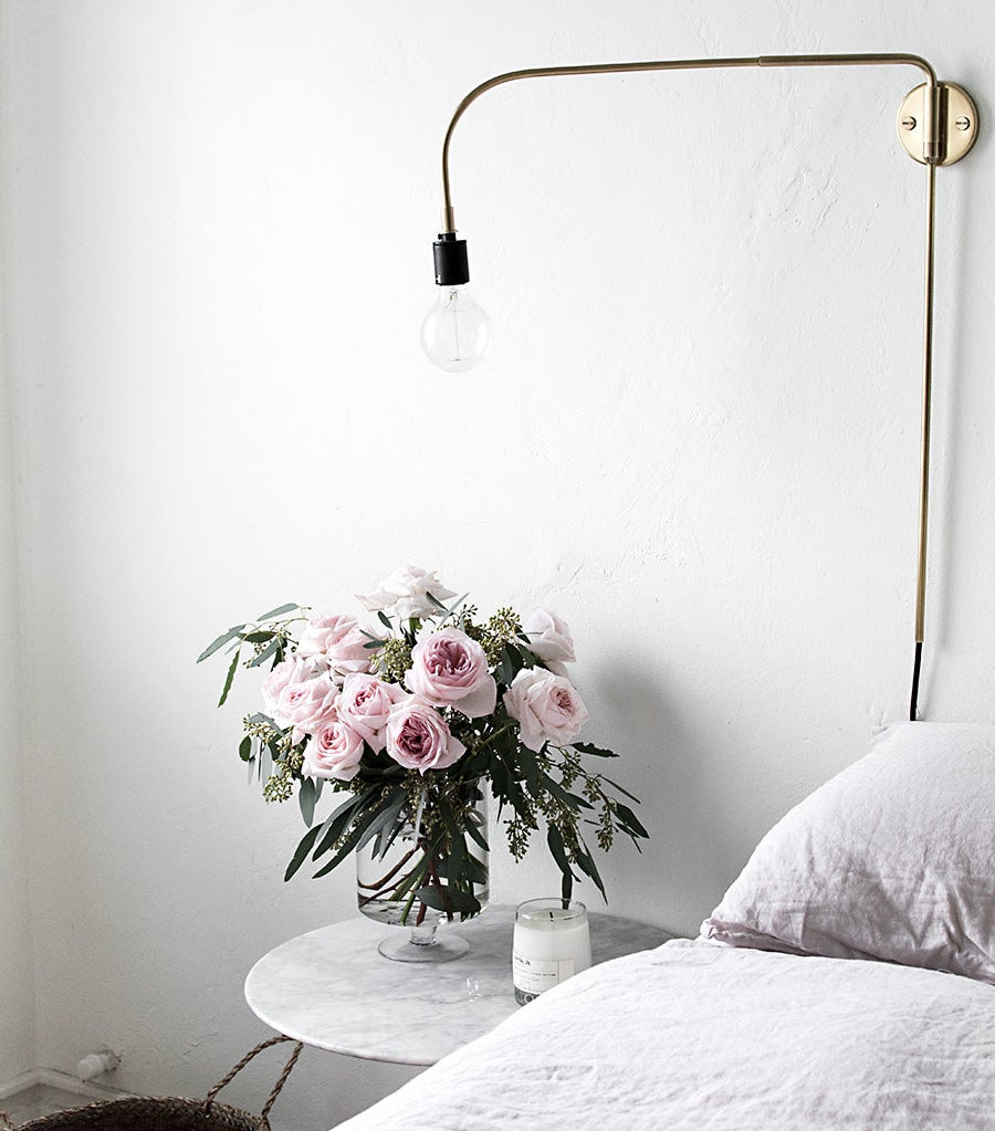 A gorgeous bouquet of pink roses sitting on a bedside table.