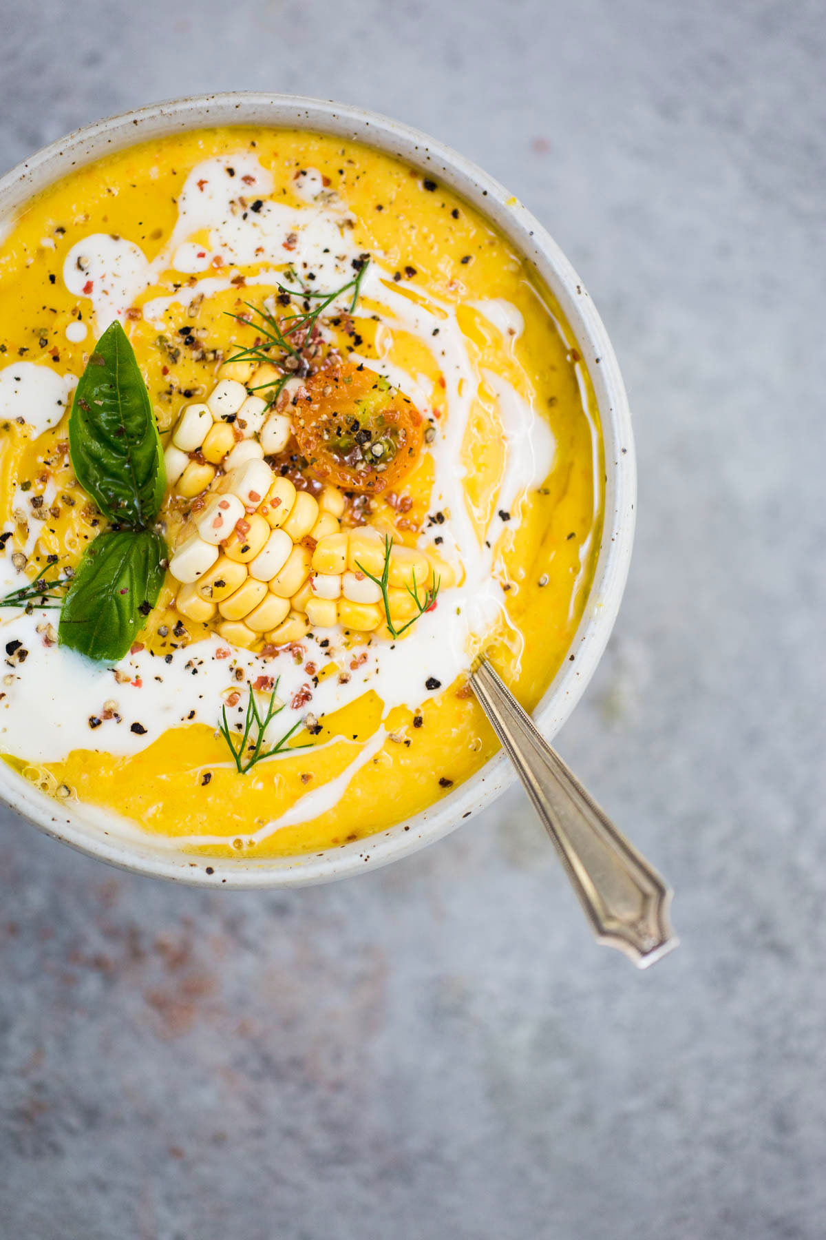 a bowl of yellow soup with corn in it