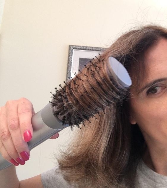 A reviewer with their hair wrapped around the brush mid–blowout