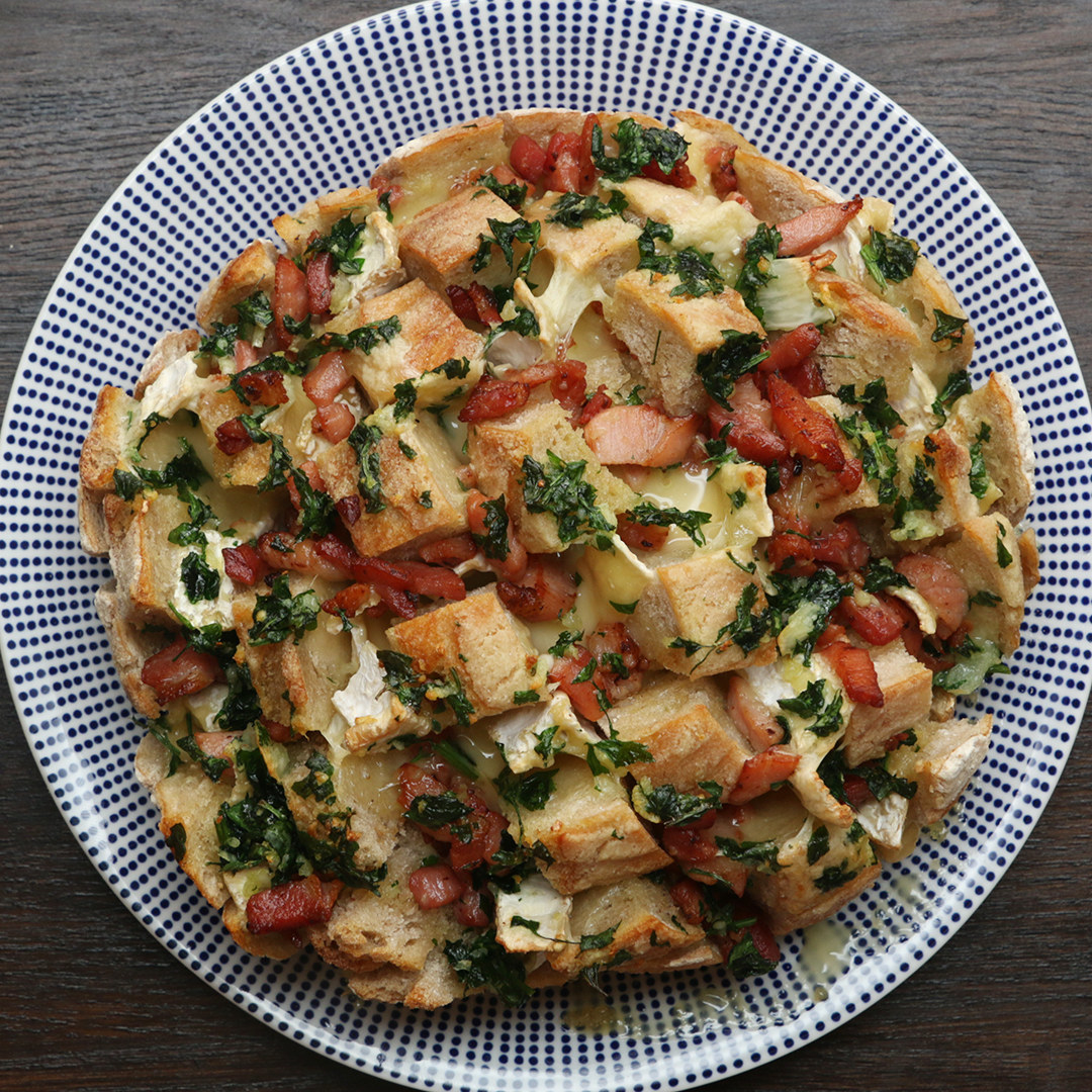 Você vai precisar de:1 pão italiano250g de queijo camembert75g de manteiga derretida10g de salsa fresca picada2 dentes de alho amassados150g de bacon cozido picadoModo de preparo:1. Preaqueça o forno a 180 °C.2. Corte fatias profundas e grossas no pão sem cortar até o fim. Gire o pão 90° e corte mais fatias, criando pequenas tiras de pão, todas unidas pela parte de baixo.3. Corte o queijo camembert em tiras grossas e enfie-as entre as tiras de pão.4. Jogue os pedaços de bacon cozido sobre o pão, empurrando alguns deles para dentro do pão.5. Misture a manteiga, a salsa e o alho, e despeje de modo uniforme sobre o pão.6. Deixe assar por 18 a 20 minutos até o queijo camembert derreter e a parte de cima do pão ficar crocante.7. Bom apetite!