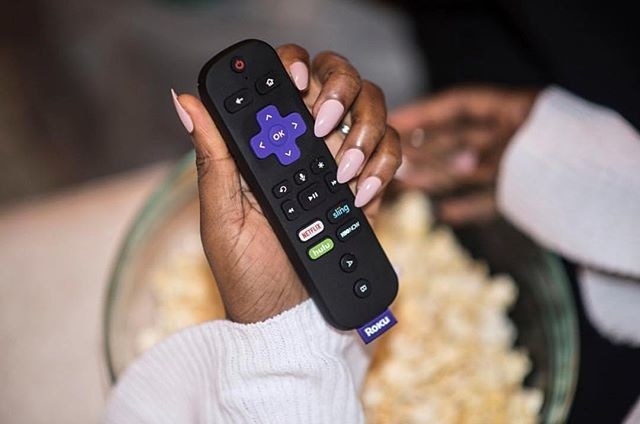 hand holds small remote with buttons for sling, netflix, and hulu