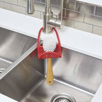 kitchen sink with dish brush in a sling over the kitchen faucet