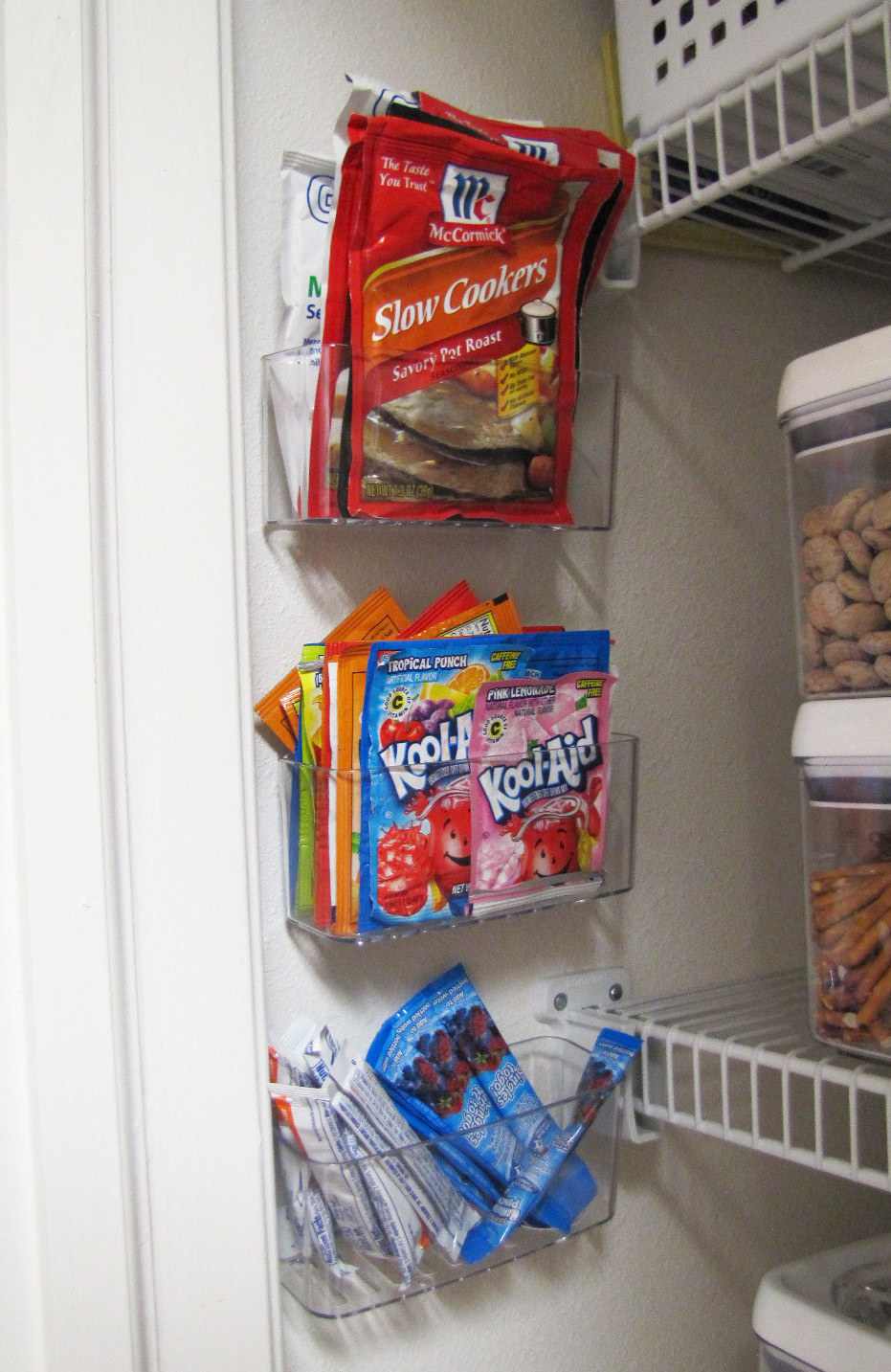 blogger photo of inside pantry in narrow expanse of wall with wall mounted clear kitchen sponge holders that hold drink and sauce packets