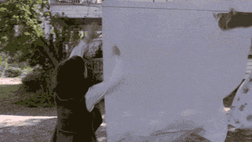 A woman trying to grab a sheet hanging on a clothesline that turns into the shape of a ghost
