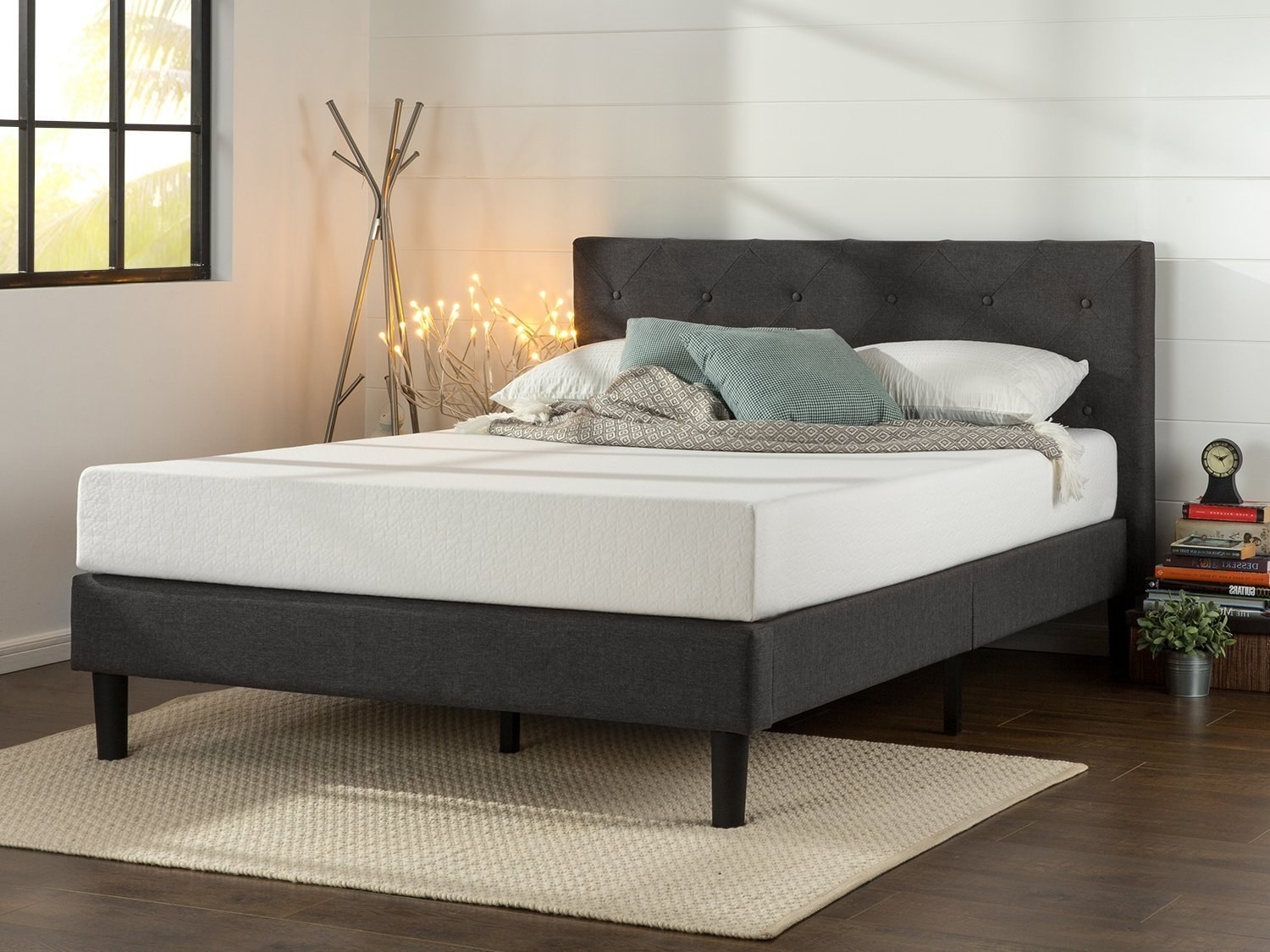 The platform bed with a tufted headboard in dark grey with a mattress on top