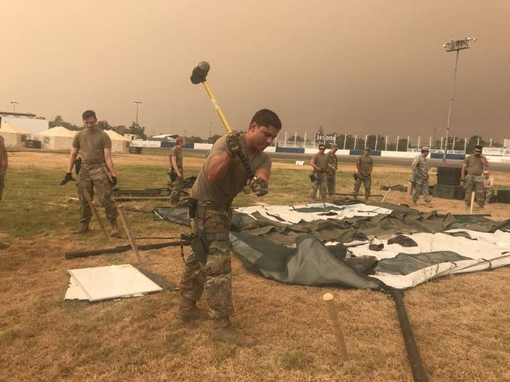 Members of the California National Guard put up a tent at the Shasta District Fairgrounds shortly after arriving in Anderson, California, to support firefighting operations for the Carr fire.