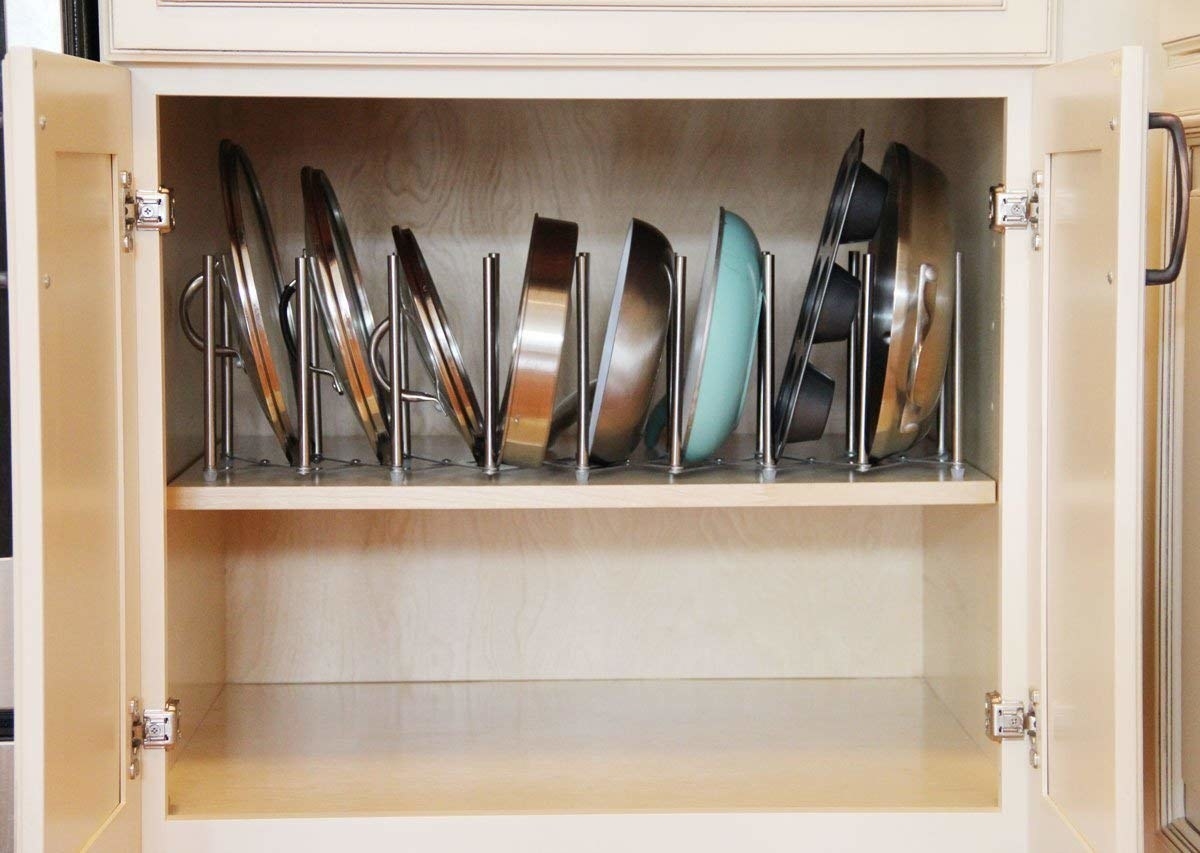 inside a kitchen cabinet with the accordion-like organizer stretched across the shelf&#x27;s length to hold pans and lids