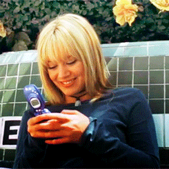 A GIF of Lizzie McGuire texting LOL on a blue Samsung flip phone.